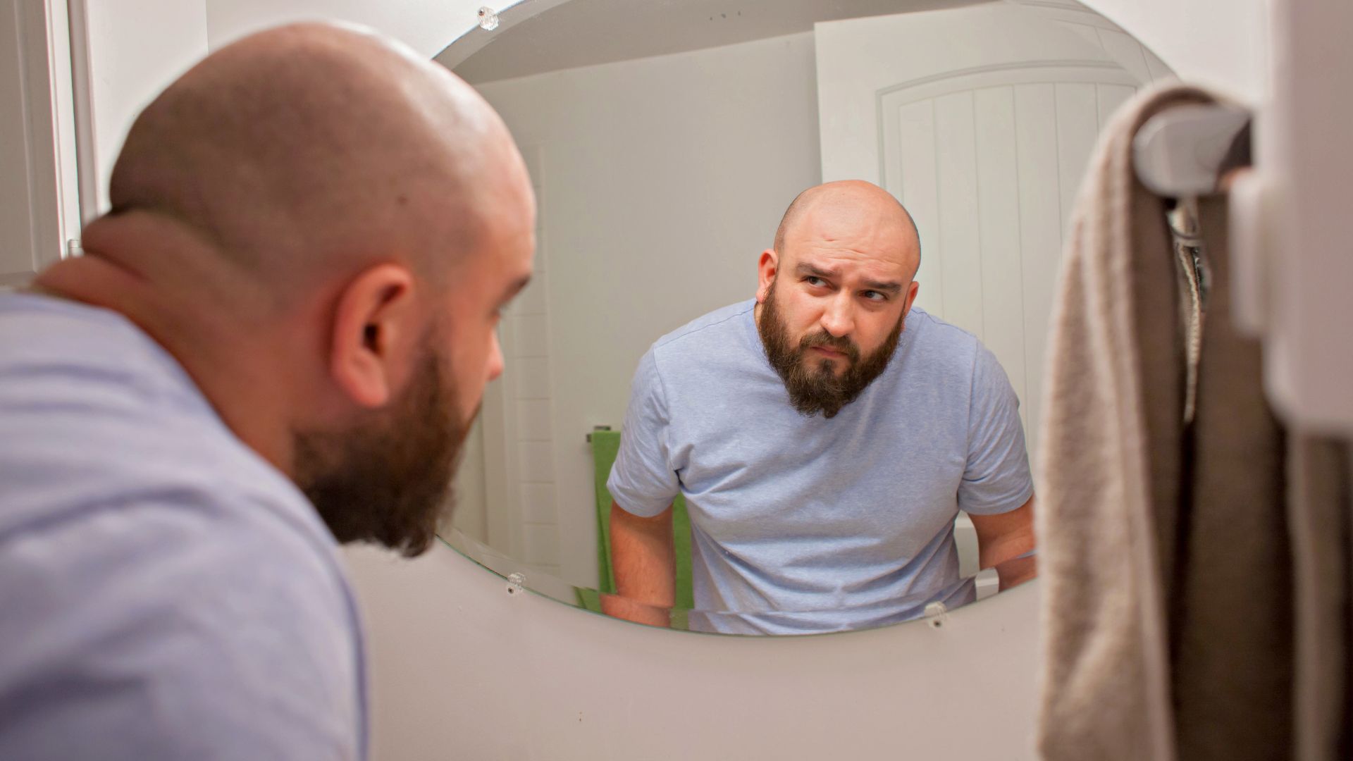 不安そうに鏡に映る自分を見ている男性